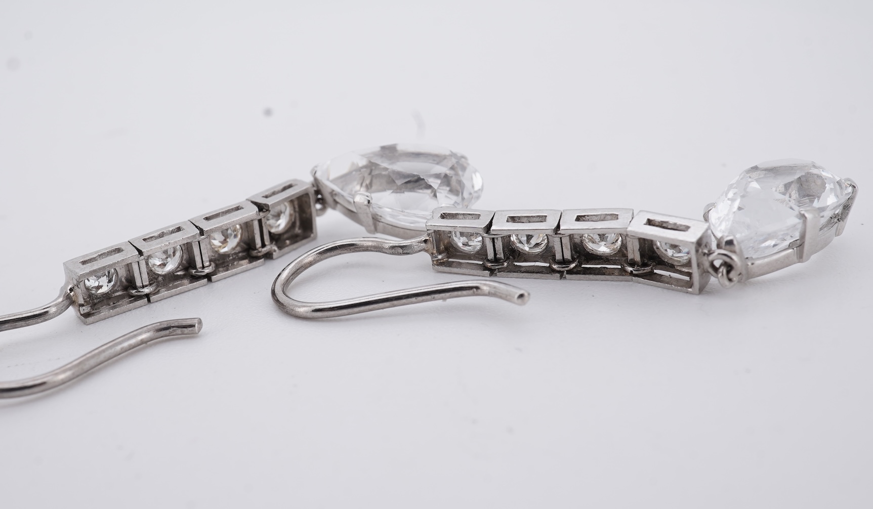 A pair of white metal and four stone diamond set earrings, each with a cubic zirconia pear shaped drop, overall 42mm.